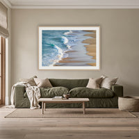 Tura Beach Waves framed print in oak with a white mat, above an olive linen sofa in a lounge room