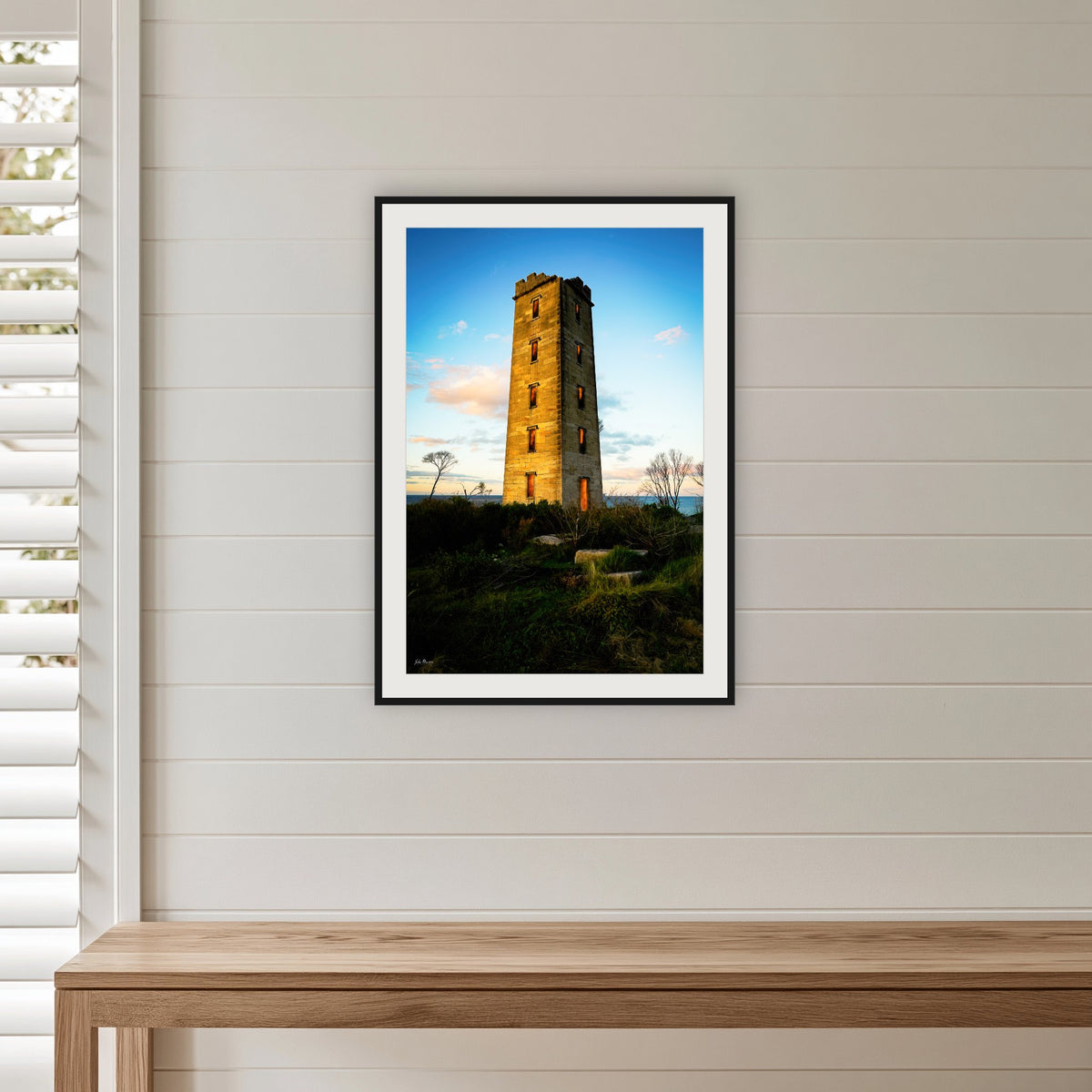 Ben Boyd Tower framed print in black with a white mat, in a shiplap hallway
