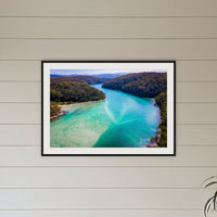 Pambula River to the Mountains framed print in black with a white mat, above a sofa