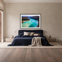 Pambula River to the Mountains framed print in black with a white mat, above a navy linen bed in a bedroom