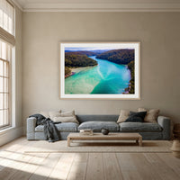 Pambula River to the Mountains framed print in oak with a white mat, above a dusty blue linen sofa in a lounge room