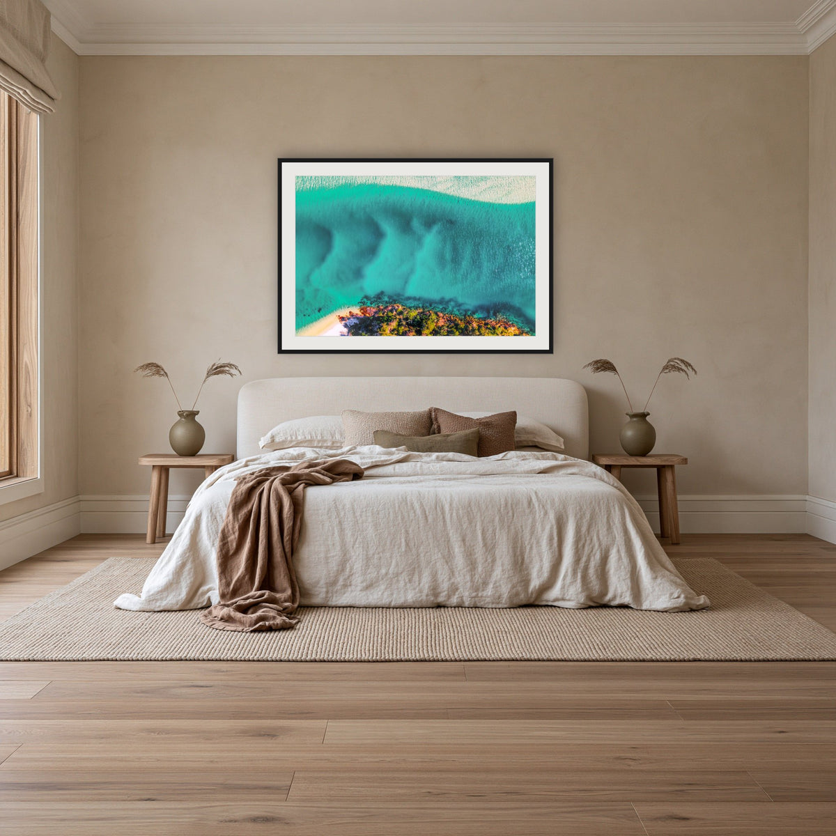 Pambula River Bird's Eye View framed print in black with a white mat, above an ivory linen bed in a bedroom