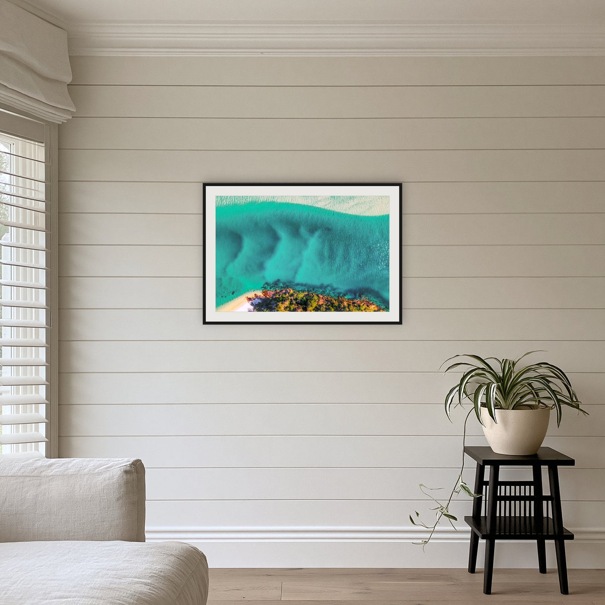 Pambula River Bird's Eye View framed print in black with a white mat, above a sofa