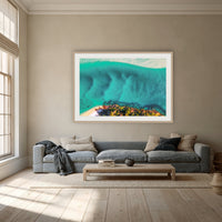 Pambula River Bird's Eye View framed print in oak with a white mat, above a dusty blue linen sofa in a lounge room