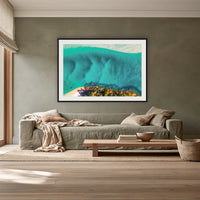 Pambula River Bird's Eye View framed print in black with a white mat, above a sage linen sofa in a lounge room