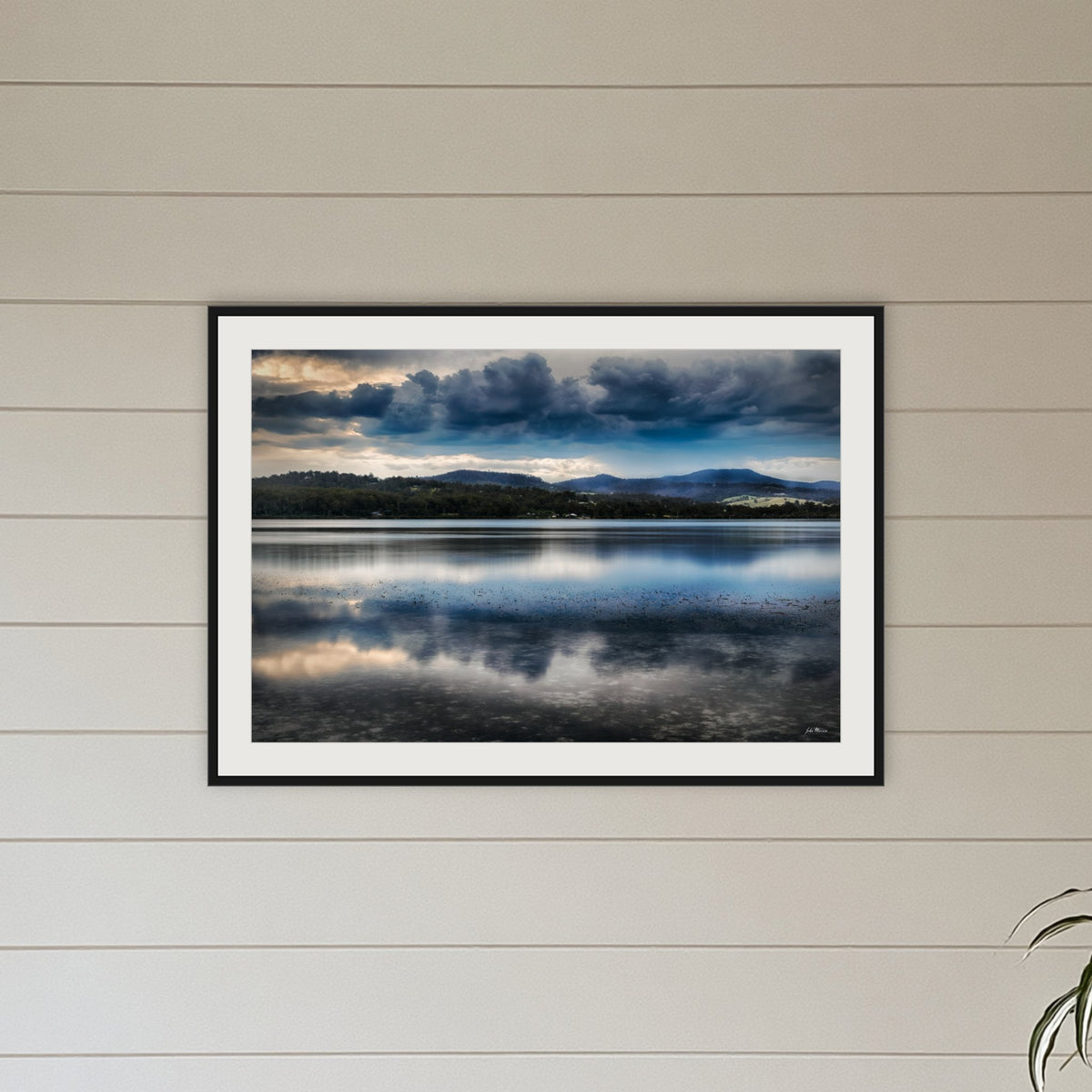 Storm Clouds over Top Lake framed print in black with a white mat, above a sofa