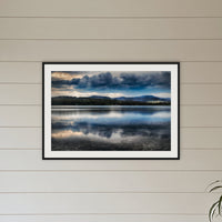 Storm Clouds over Top Lake framed print in black with a white mat, above a sofa