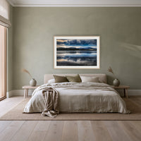 Storm Clouds over Top Lake framed print in oak with a white mat, above a linen bed against a sage wall in a bedroom