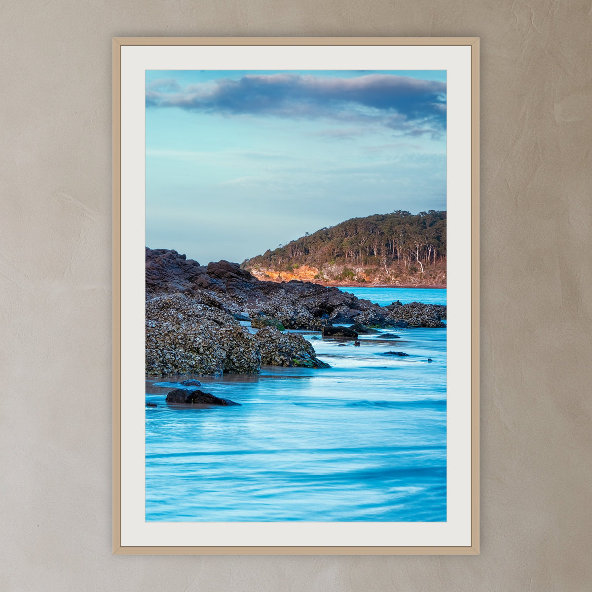 Pambula River Oyster Leases framed print in oak with a white mat, in a plaster-walled hallway
