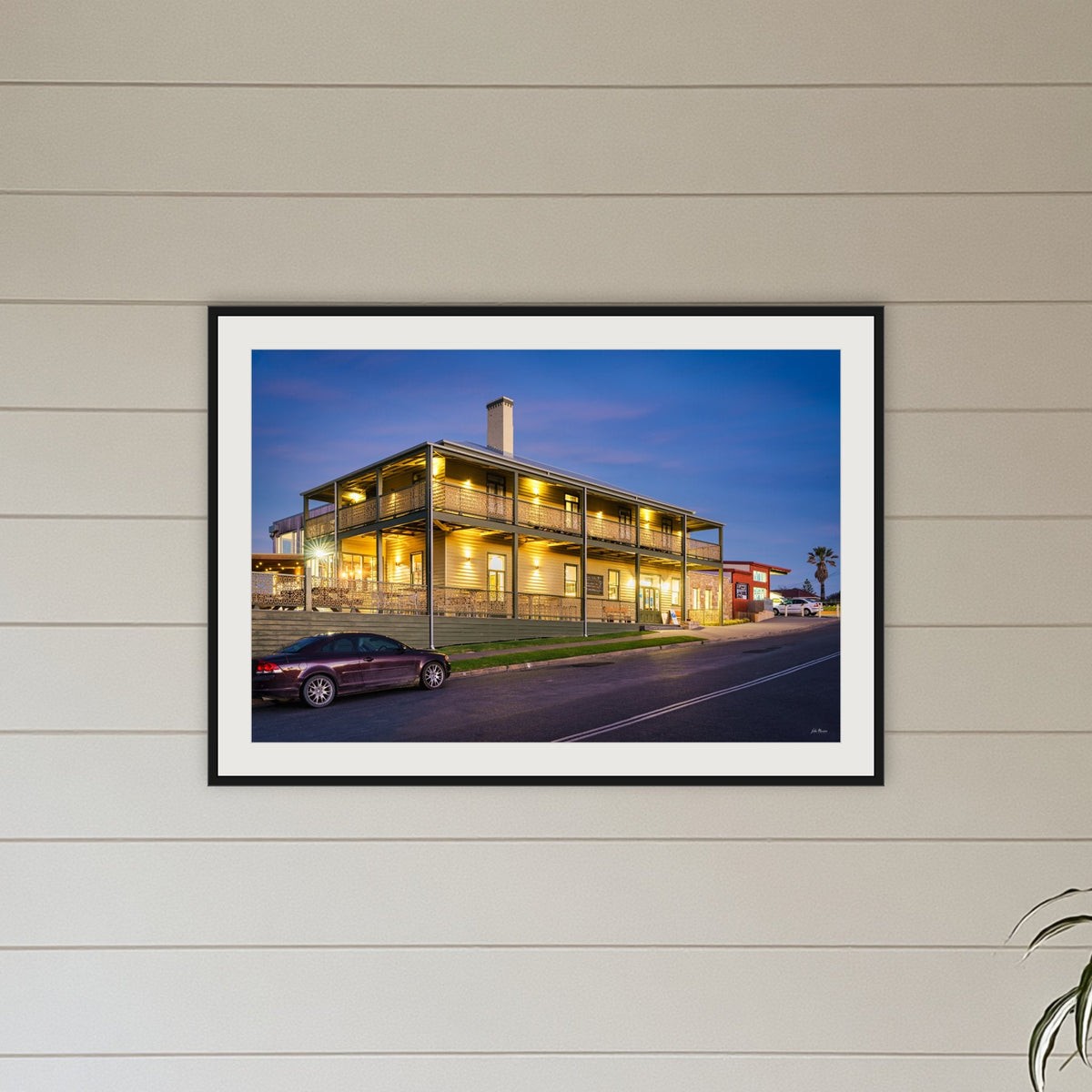 Tathra Hotel framed print in black with a white mat, above a sofa