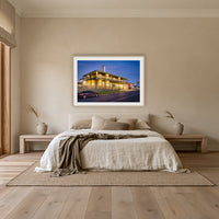 Tathra Hotel framed print in oak with a white mat, above an oatmeal linen bed in a bedroom
