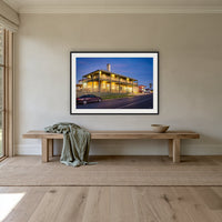 Tathra Hotel framed print in black with a white mat, above an oak bench in a hallway