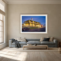 Tathra Hotel framed print in oak with a white mat, above a dusty blue linen sofa in a lounge room