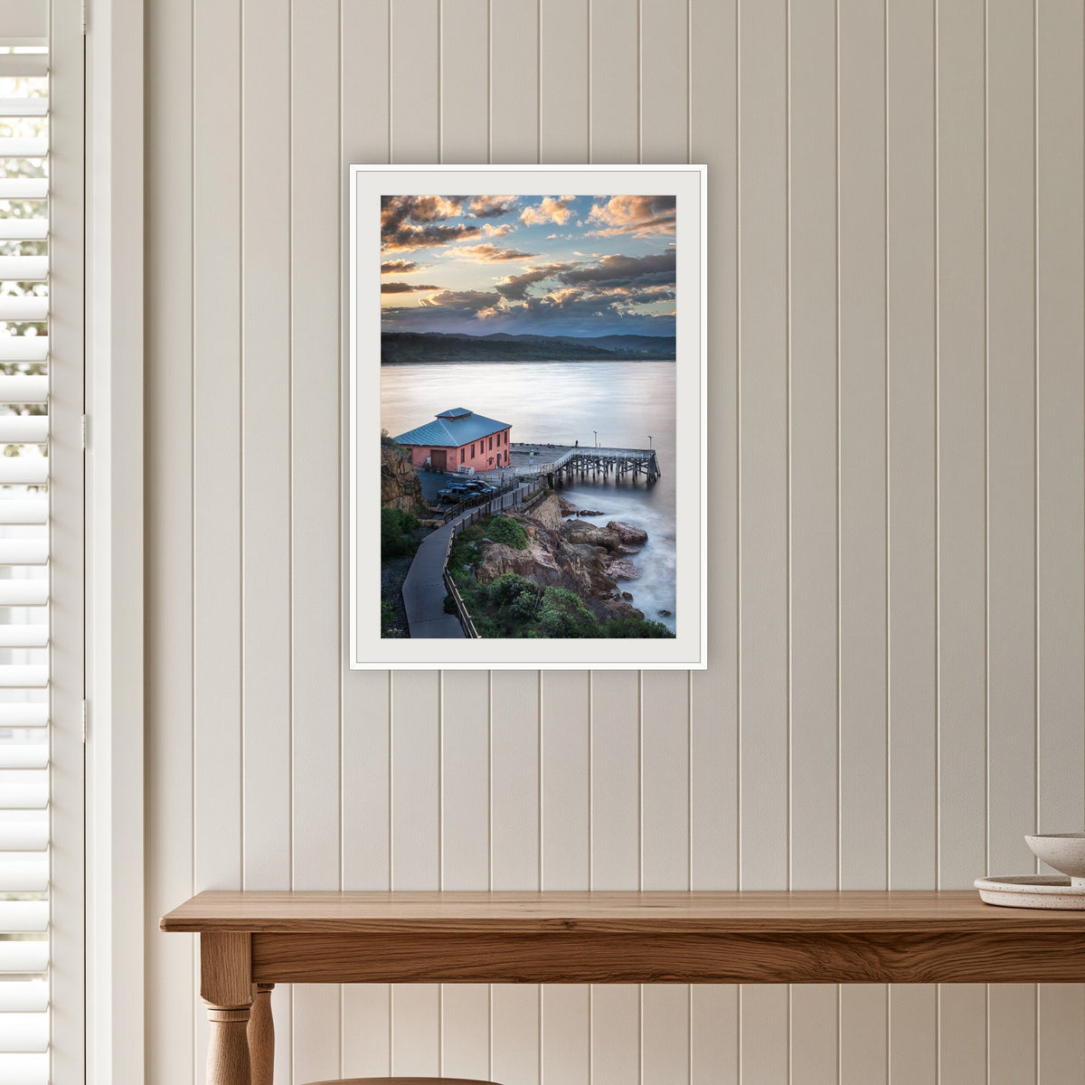 Tathra Wharf Smooth Seas framed print in white with a mat, on a panelled hallway wall