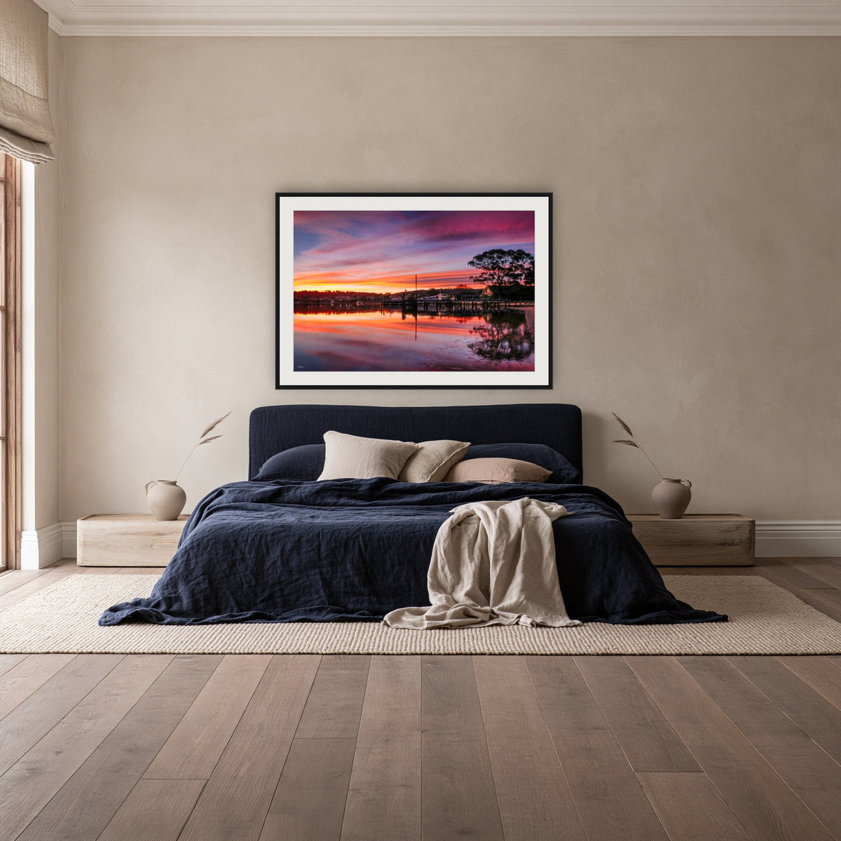 Spencer Park framed print in black with a white mat, above a navy linen bed in a bedroom