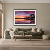 Spencer Park Sunset framed print in black with a white mat, above an olive linen sofa in a lounge room