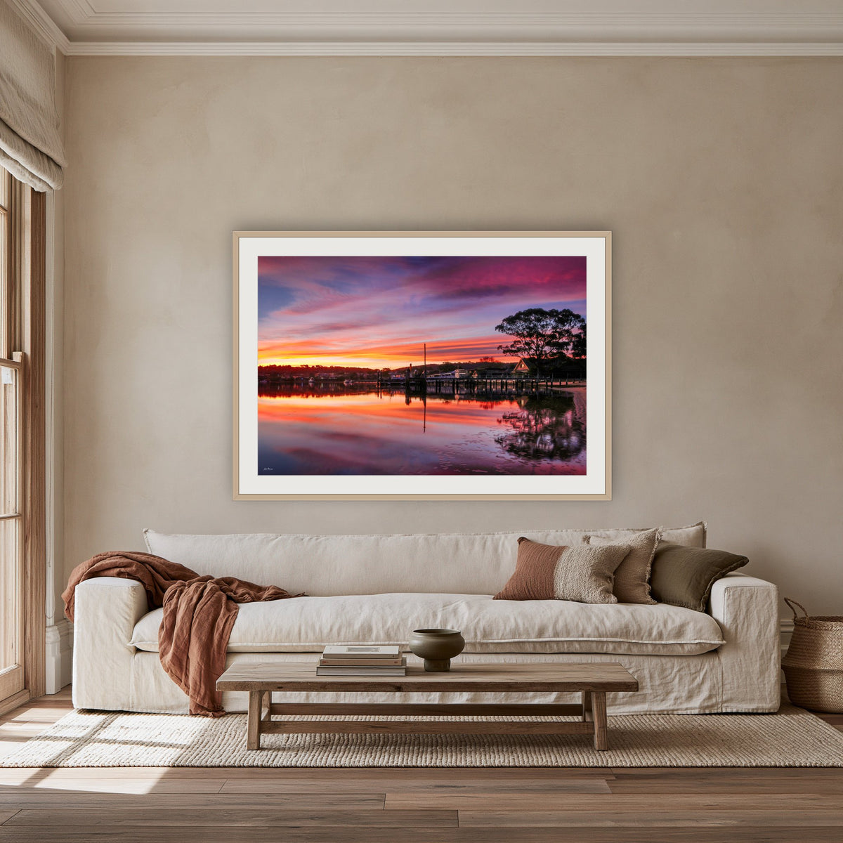 Spencer Park Sunset framed print in oak with a white mat, above an oatmeal linen sofa in a lounge room