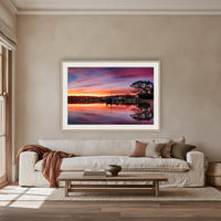 Spencer Park Sunset framed print in oak with a white mat, above an oatmeal linen sofa in a lounge room