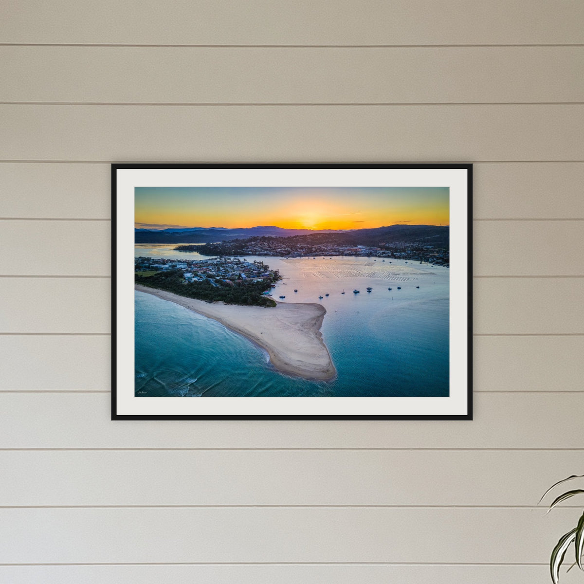 Fishpen Aerial View framed print in black with a white mat, above a sofa