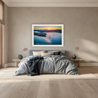 Fishpen Aerial View framed print in oak with a white mat, above a dusty blue linen bed in a bedroom