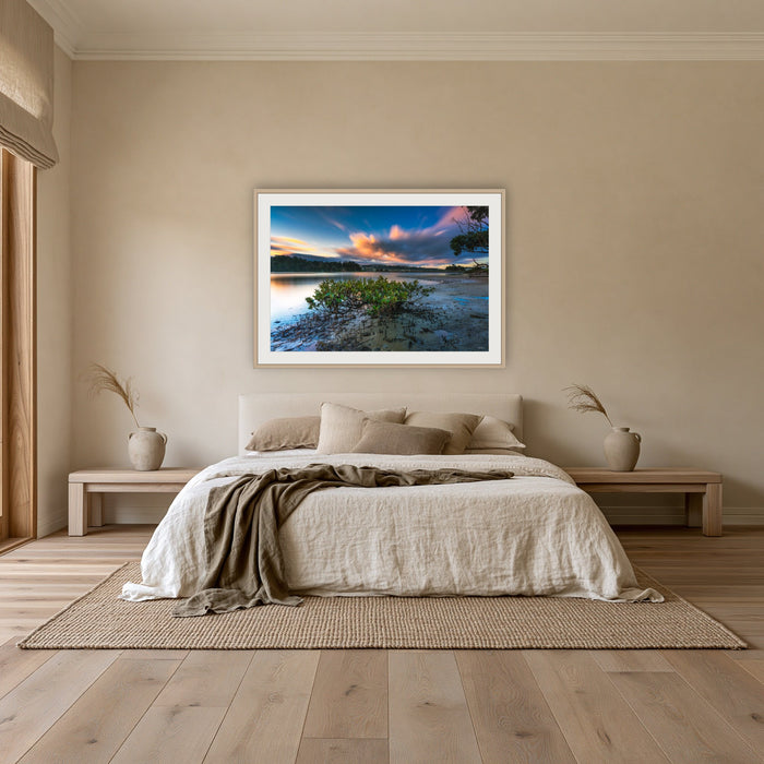 Merimbula through a Mangrove Tree framed print in oak with a white mat, above an oatmeal linen bed in a bedroom