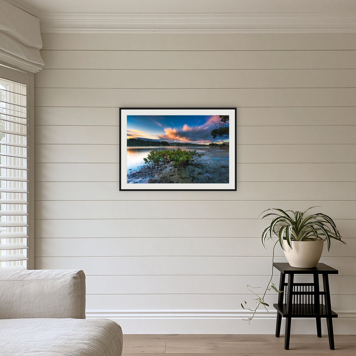 Merimbula through a Mangrove Tree framed print in black with a white mat, above a sofa
