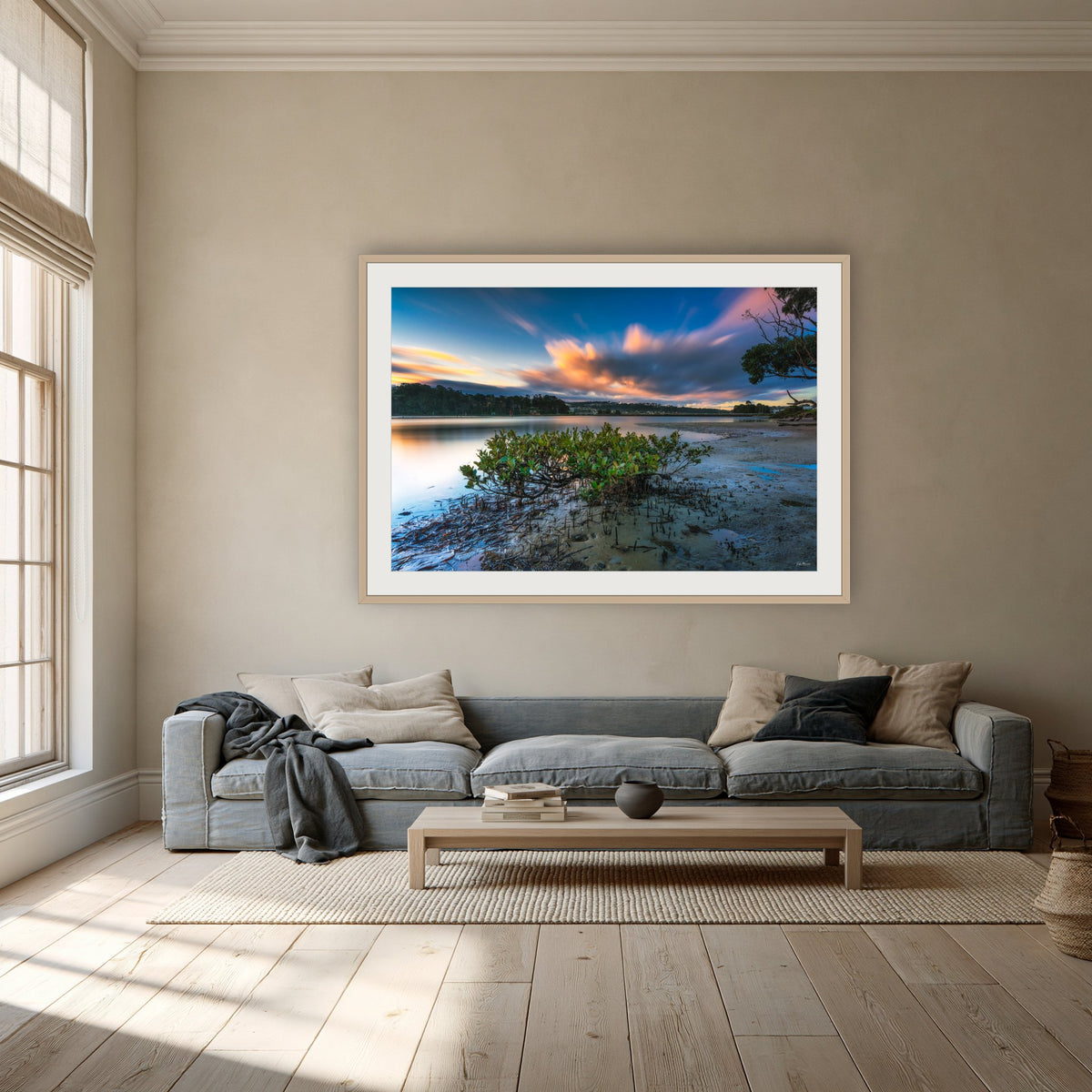 Merimbula through a Mangrove Tree framed print in oak with a white mat, above a dusty blue linen sofa in a lounge room