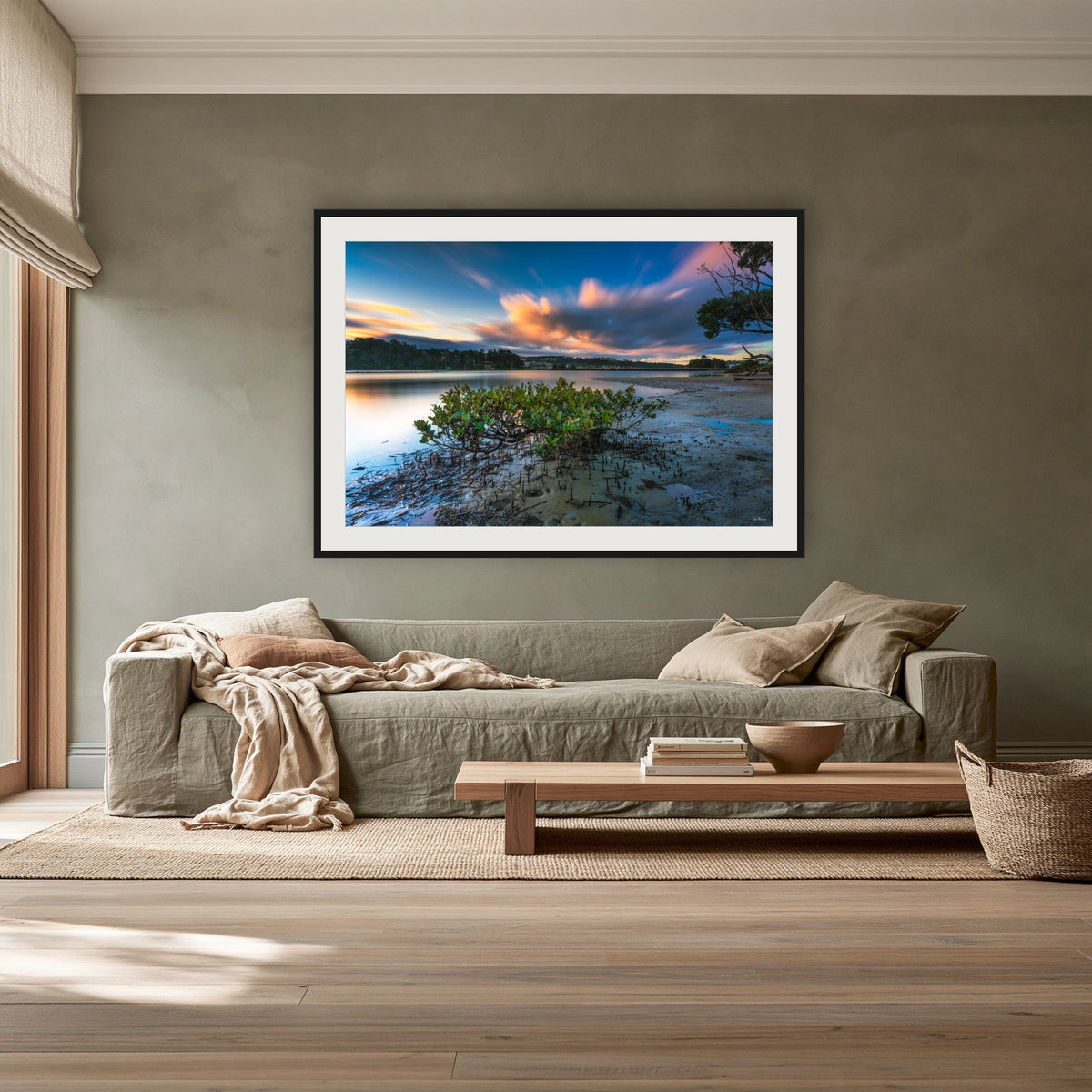 Merimbula through a Mangrove Tree framed print in black with a white mat, above a sage linen sofa in a lounge room