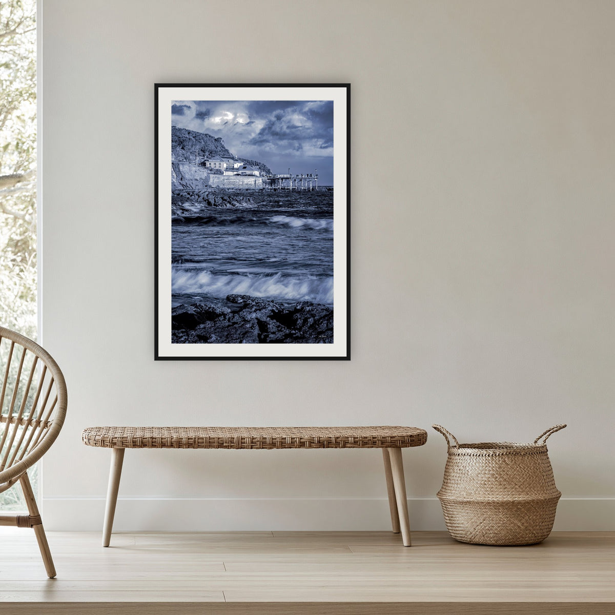 Merimbula Wharf framed print in black with a white mat, in a cane-panelled hallway