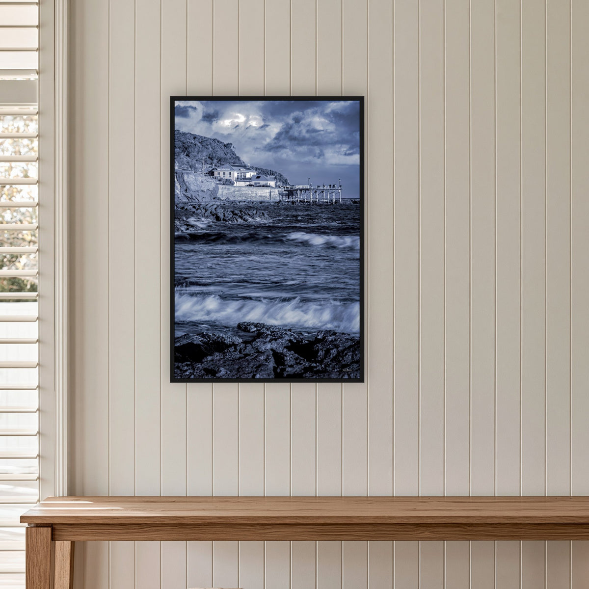 Merimbula Wharf in a black frame without a mat, on a panelled hallway wall