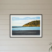 Pambula River Sea Entrance framed print in black with a white mat, above a sofa