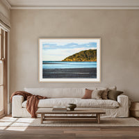 Pambula River Sea Entrance framed print in oak with a white mat, above an oatmeal linen sofa in a lounge room