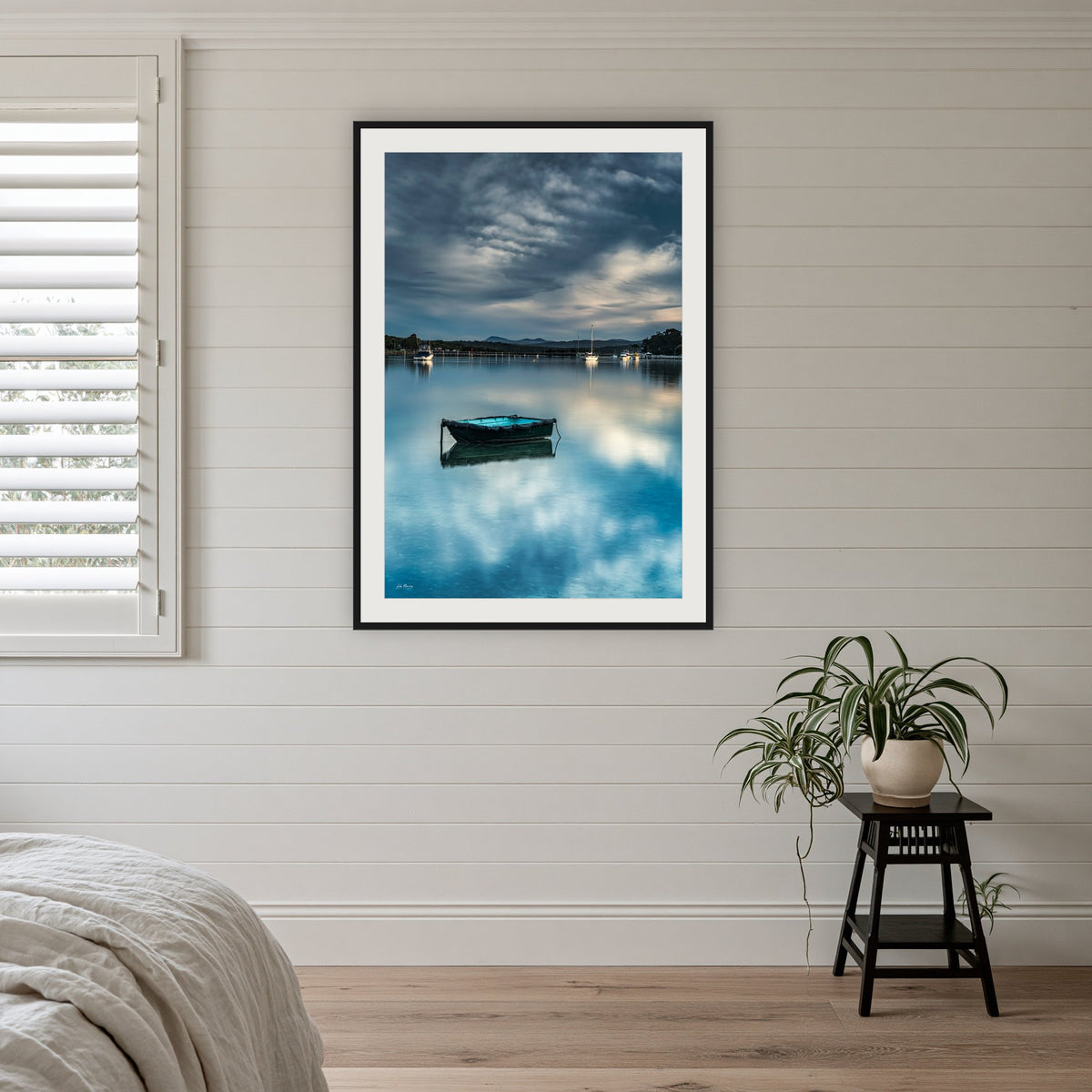 Little Boat framed print in black with a white mat, on a coastal bedroom wall
