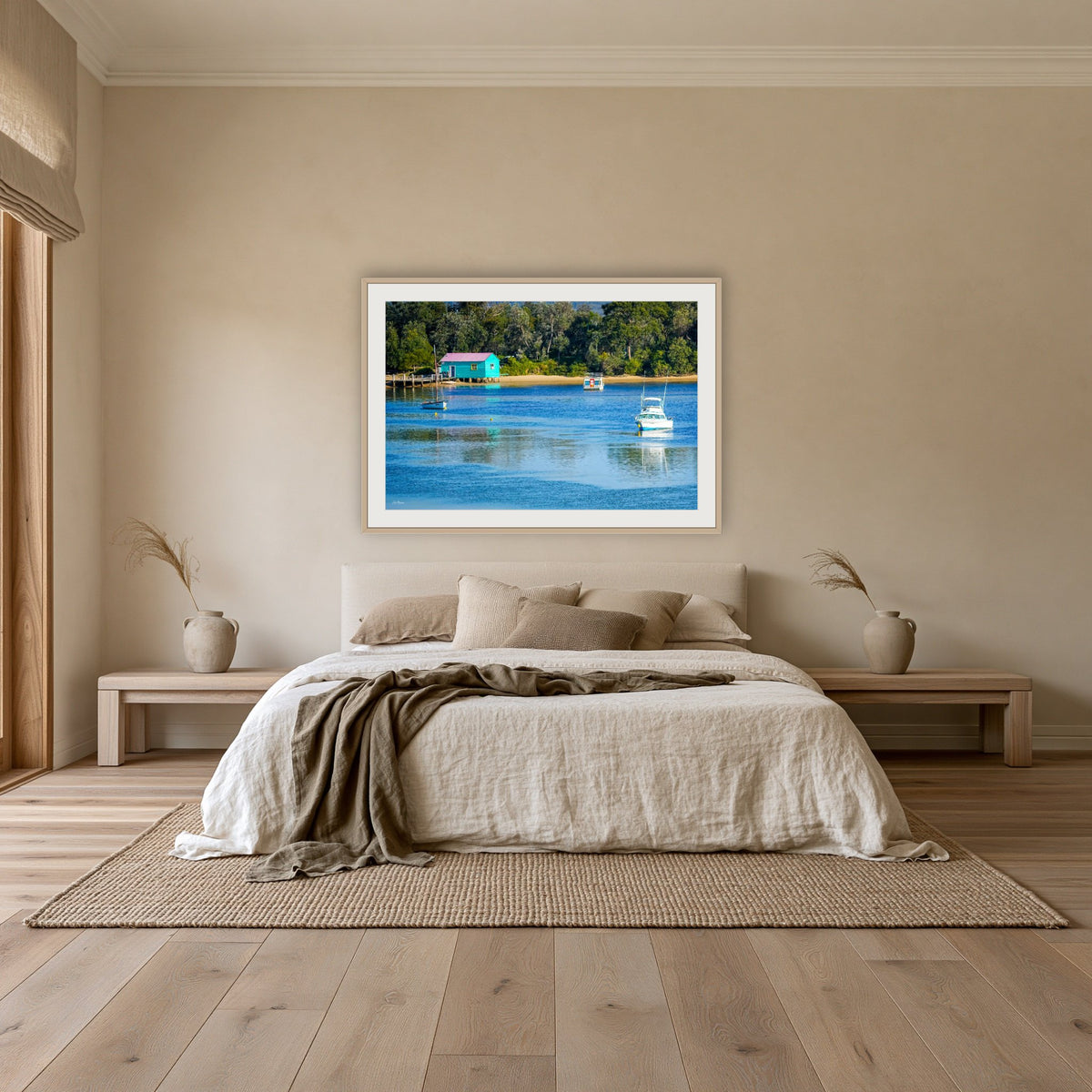 Mitchies Jetty framed print in oak with a white mat, above an oatmeal linen bed in a bedroom