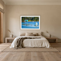 Mitchies Jetty framed print in oak with a white mat, above an oatmeal linen bed in a bedroom