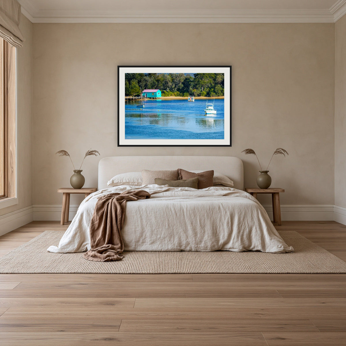 Mitchies Jetty framed print in black with a white mat, above an ivory linen bed in a bedroom