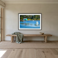 Mitchies Jetty framed print in black with a white mat, above an oak bench in a hallway