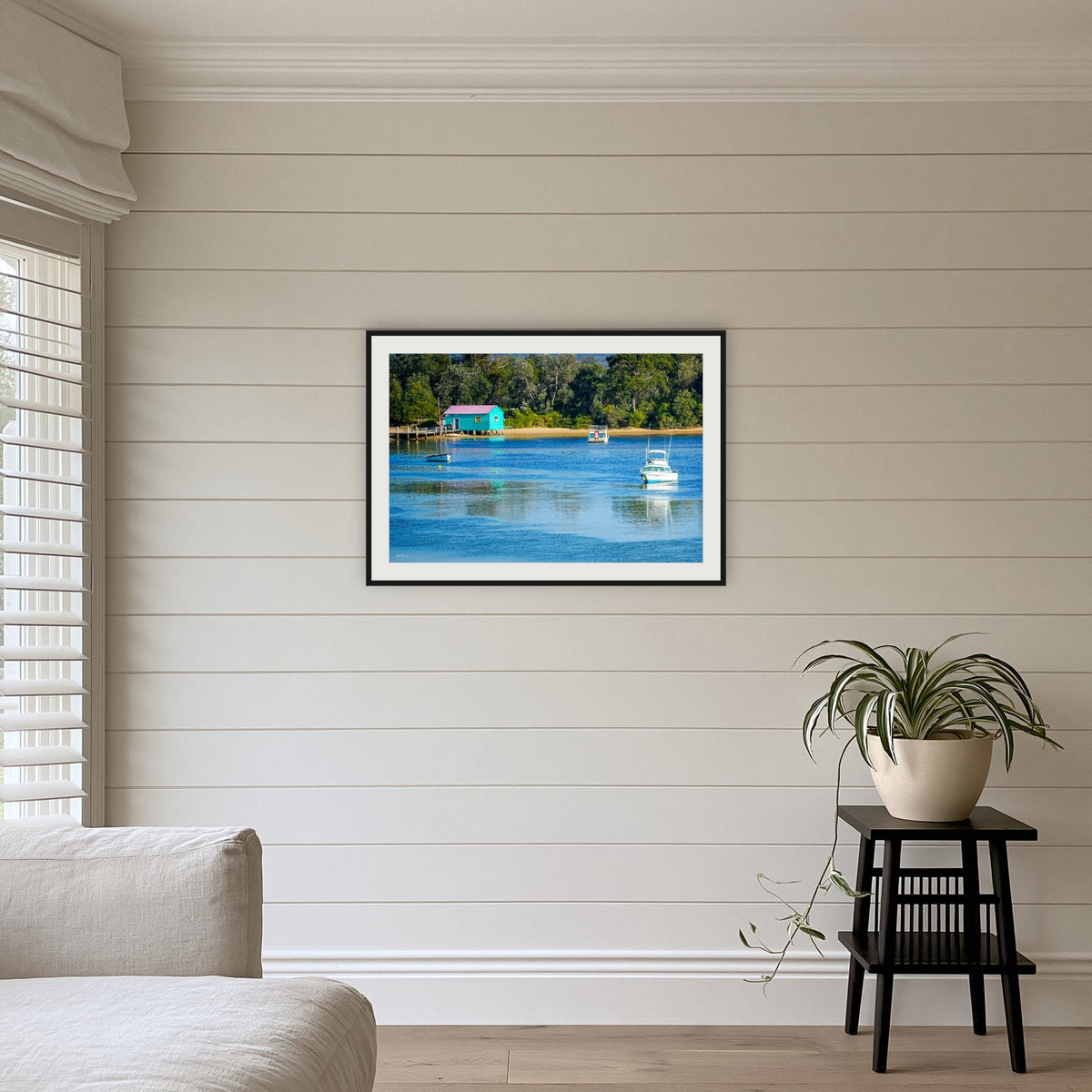 Mitchies Jetty framed print in black with a white mat, above a sofa