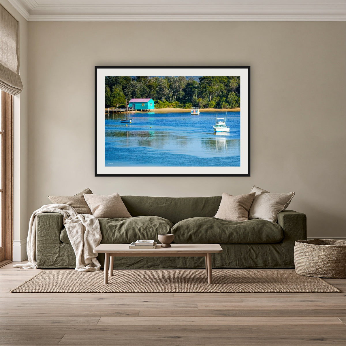 Mitchies Jetty framed print in black with a white mat, above an olive linen sofa in a lounge room