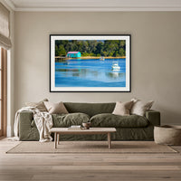 Mitchies Jetty framed print in black with a white mat, above an olive linen sofa in a lounge room