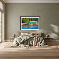 Mitchies Jetty Close Up framed print in black with a white mat, above a khaki linen bed against a green-grey wall in a bedroom
