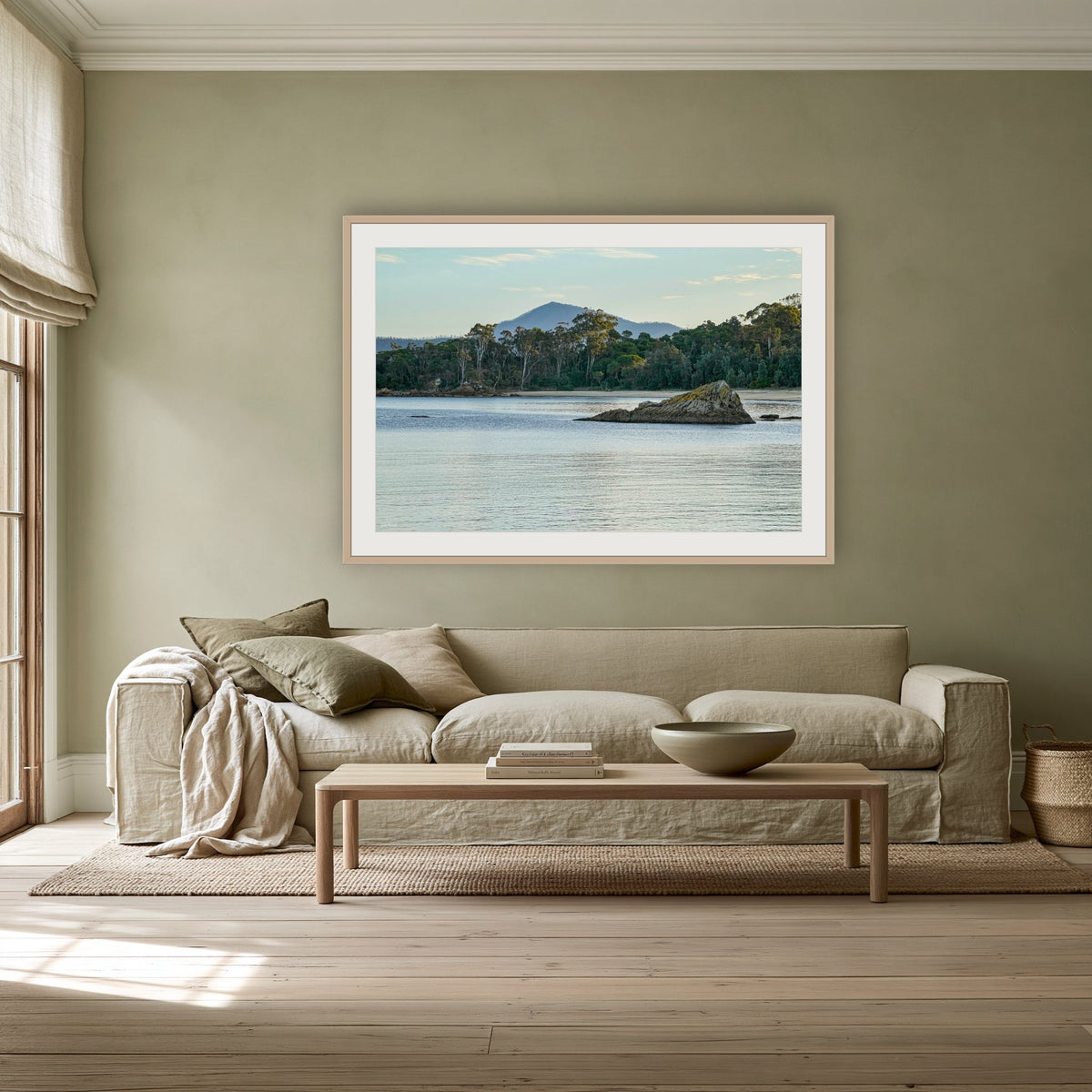 Twofold Bay, Eden framed print in oak with a white mat, above a linen sofa against a sage wall in a lounge room