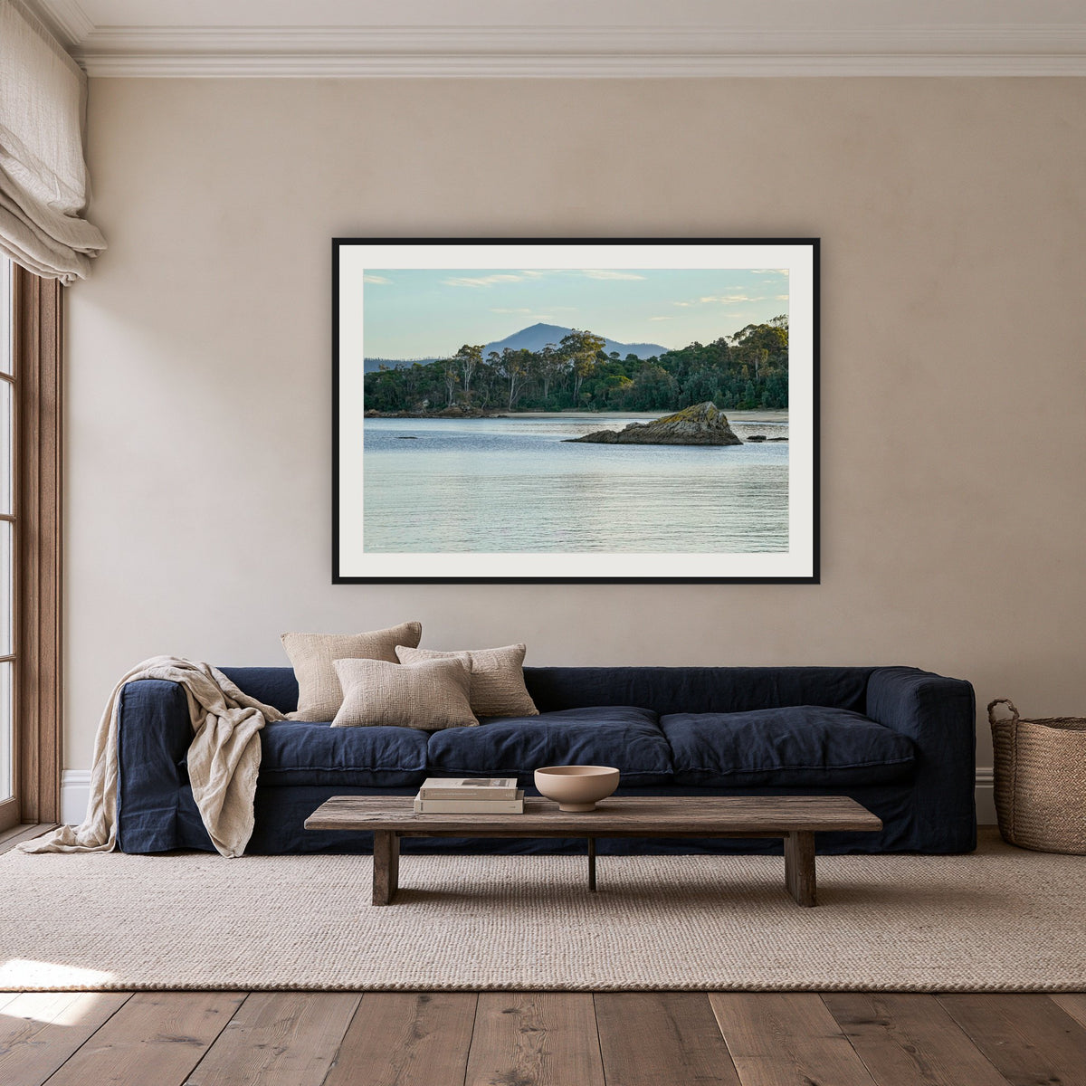 Twofold Bay, Eden framed print in black with a white mat, above a navy linen sofa in a lounge room