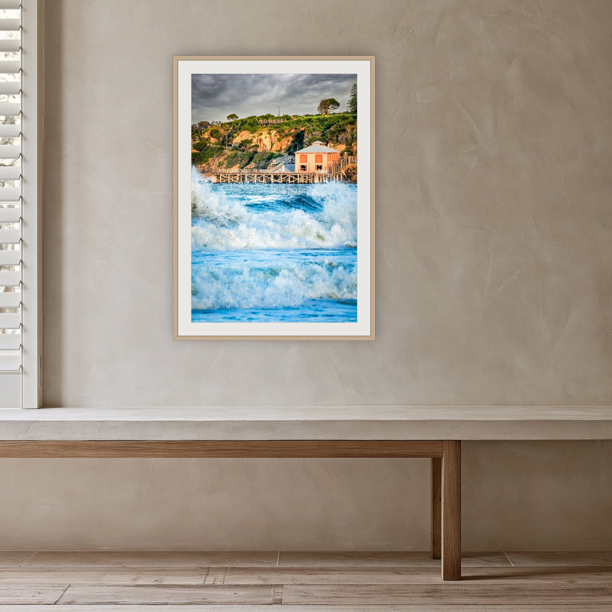 Tathra Wharf and Waves framed print in oak with a white mat, in a plaster-walled hallway