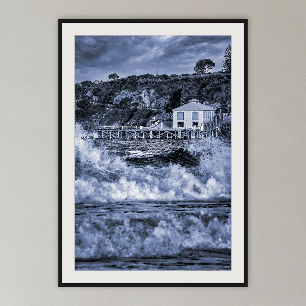 Tathra Wharf and Waves in black and white, framed print in black with a white mat, in a cane-panelled hallway
