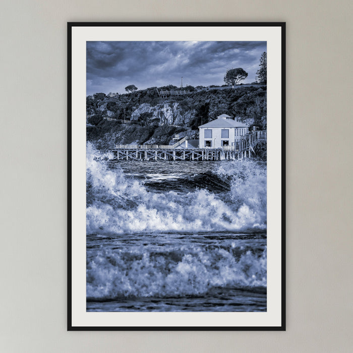 Tathra Wharf and Waves in black and white, framed print in black with a white mat, in a cane-panelled hallway