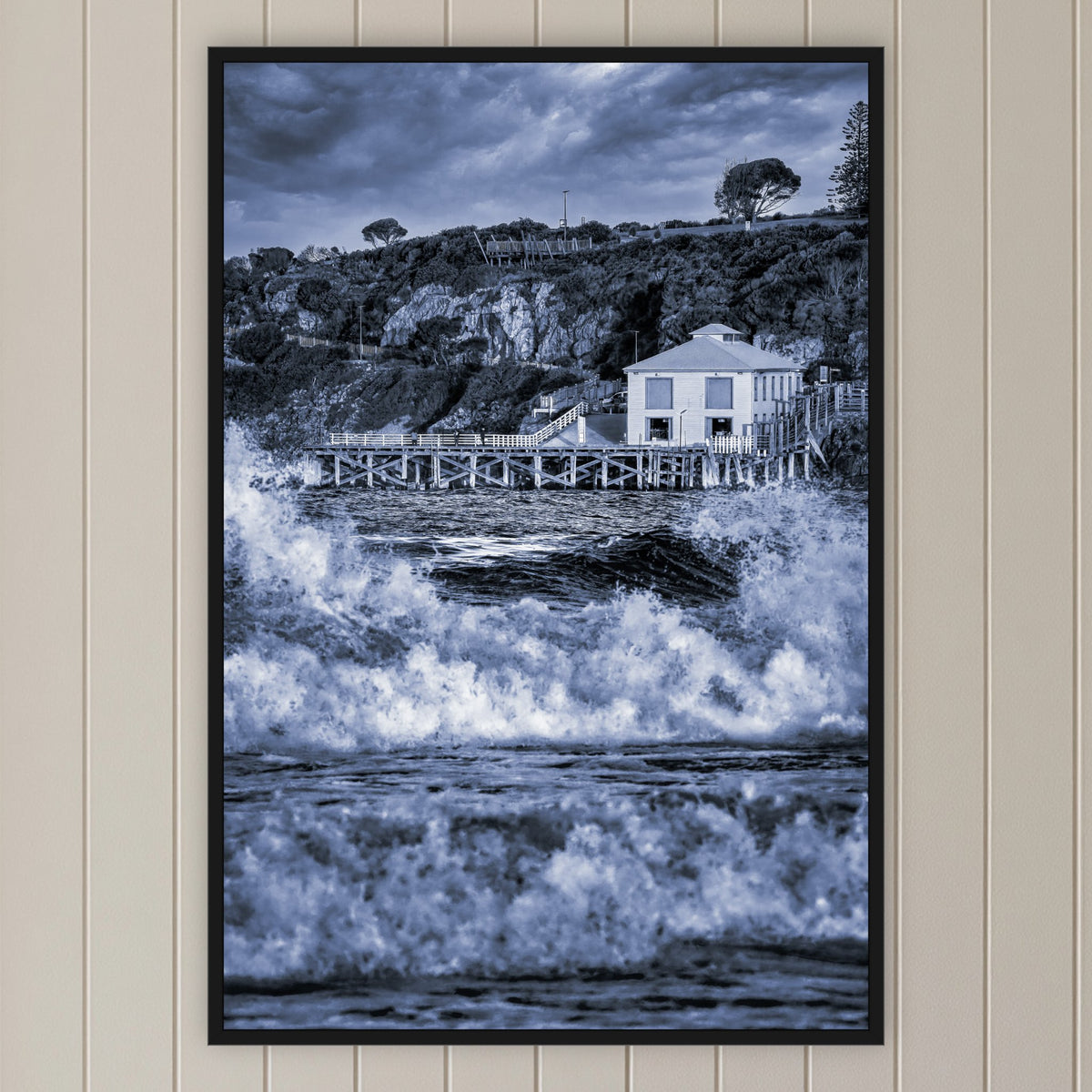 Tathra Wharf and Waves in black and white, in a black frame without a mat, on a panelled hallway wall