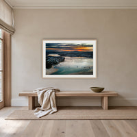 Merimbula Eagle Eye Sunset framed print in oak with a white mat, above an oak bench in a hallway