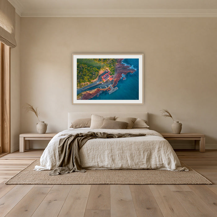 Merimbula Wharf framed print in oak with a white mat, above an oatmeal linen bed in a bedroom