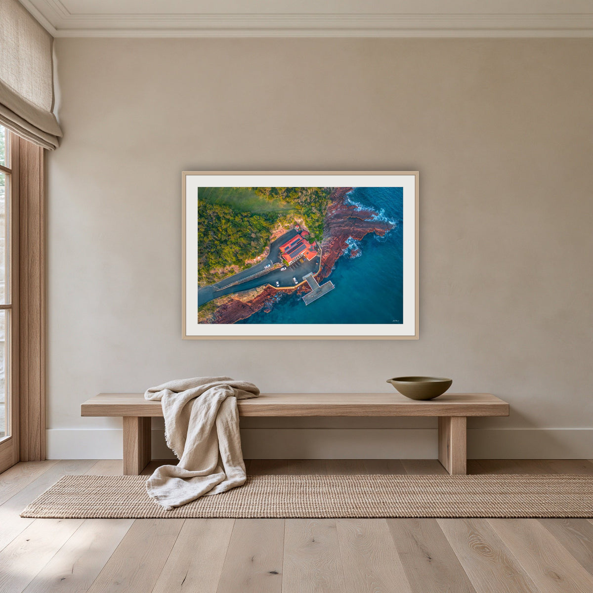 Merimbula Wharf framed print in oak with a white mat, above an oak bench in a hallway